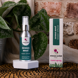 Sweet Wild ocean soul room spray bottle and packaging on a textured surface with plants and brick wall in the background