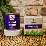 Candle labeled 'silent night' by Sweet Wild on a woven surface with a brick wall background