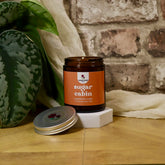 Jar of 'sugar cabin' candle with a plant and fabric in the background