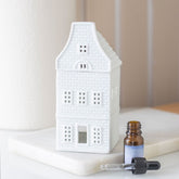 White house-shaped diffuser with a bottle and dropper on a white surface