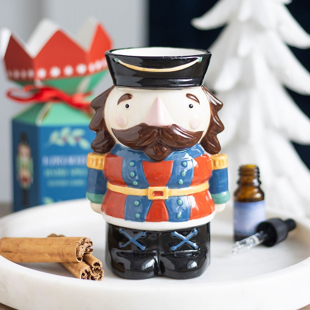 Decorative mug shaped like a man in a colorful outfit with a beard, on a surface with cinnamon sticks and a bottle.